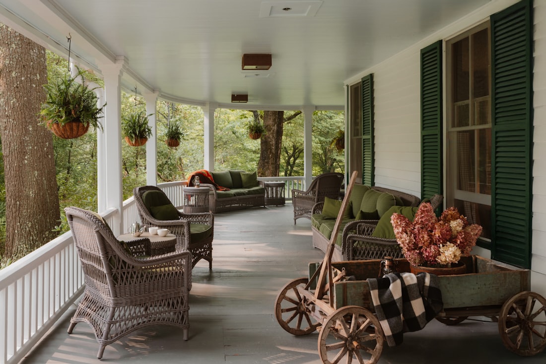 Wraparound porch with wicker seating and green shutters